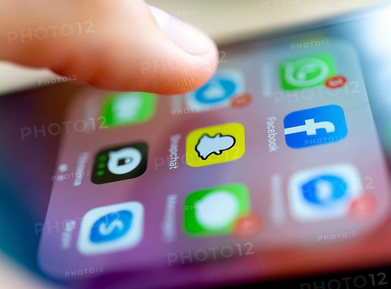 Finger tapping on screen with app icons of messenger services and social networks