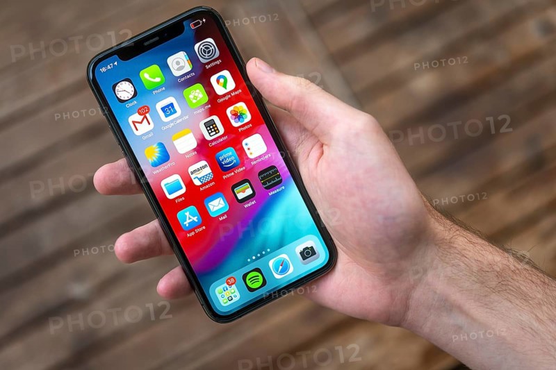 Hand haelt iPhone 11 Pro mit Homescreen