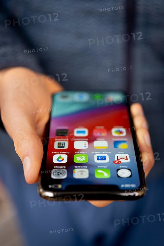 Hand haelt iPhone 11 Pro mit Homescreen