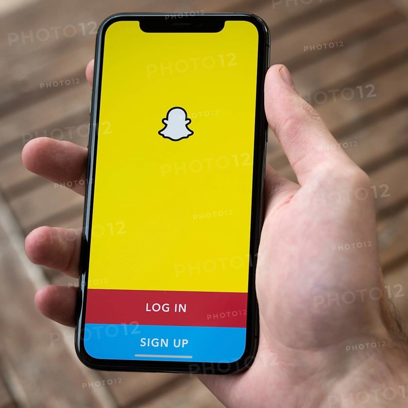 Hand haelt iPhone 11 Pro mit geoeffneter Snapchat App