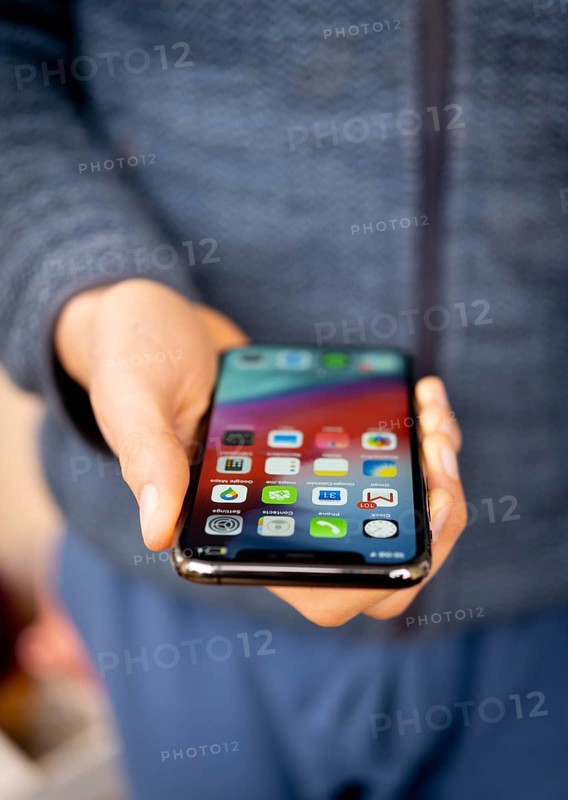 Hand haelt iPhone 11 Pro mit Homescreen