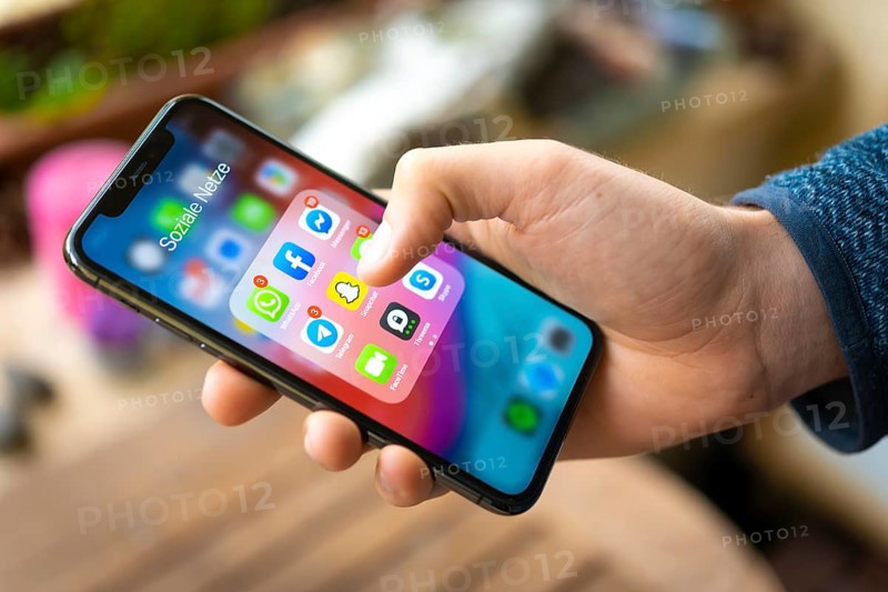 Hand haelt iPhone 11 Pro mit App-Icons von Messenger Diensten und Sozialen Netzwerken