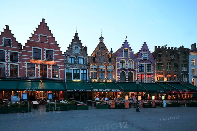 Market with residential buildings and restaurants on the north side of the square at dusk