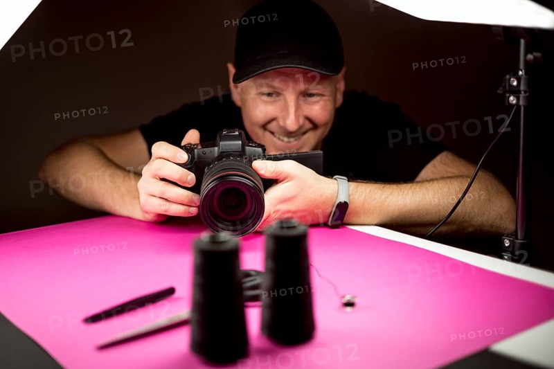 A photographer taking a photo of black tailoring accessories in the studio
