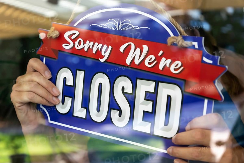 Female store owner turning sign to closed in window
