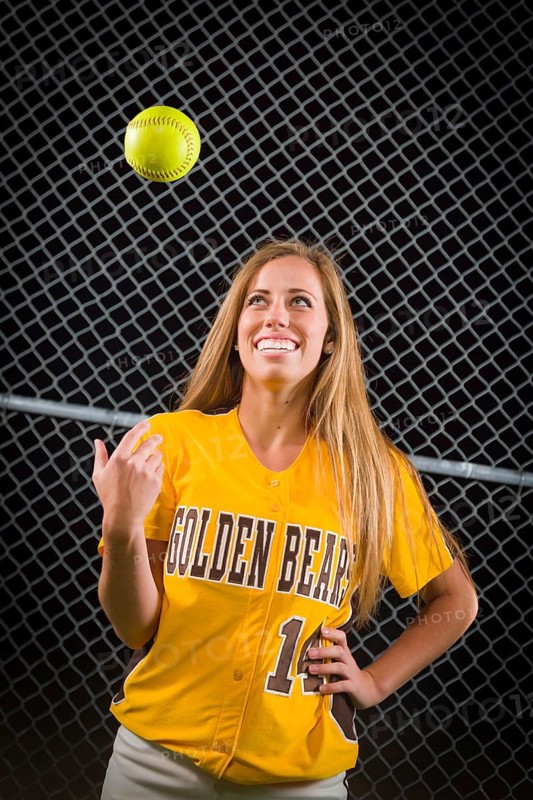 Young female softball player portrait with ball in the air