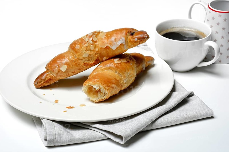 Almond croissant on plate with coffee cup
