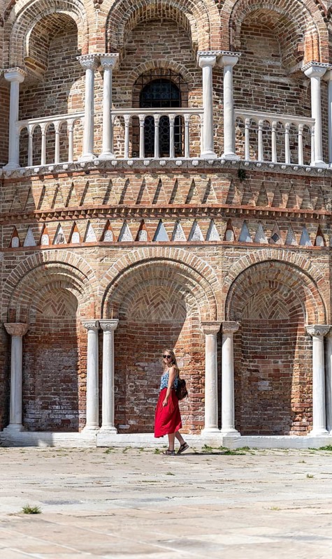 Young woman in red dress standing in front of Basilica dei Santi Maria e Donato