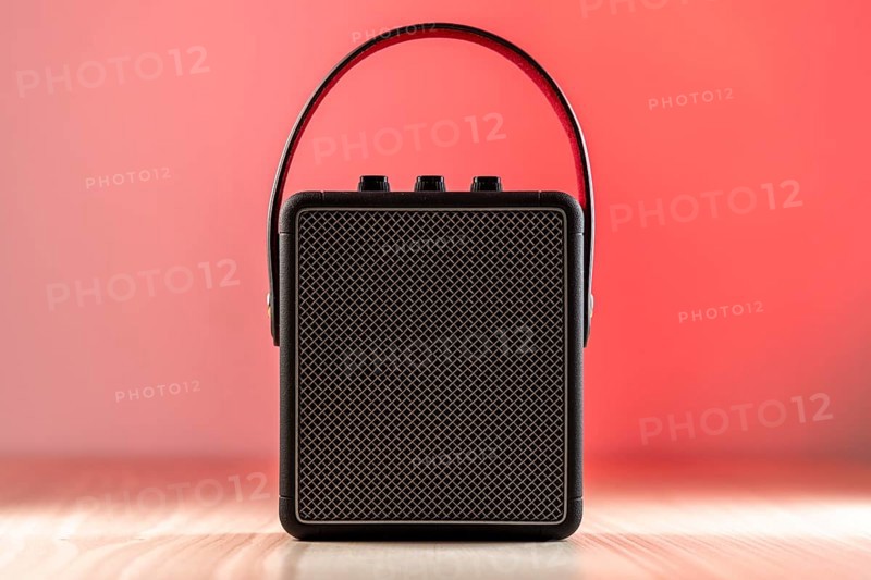 Black modern bluetooth loudspeaker on a reddish background