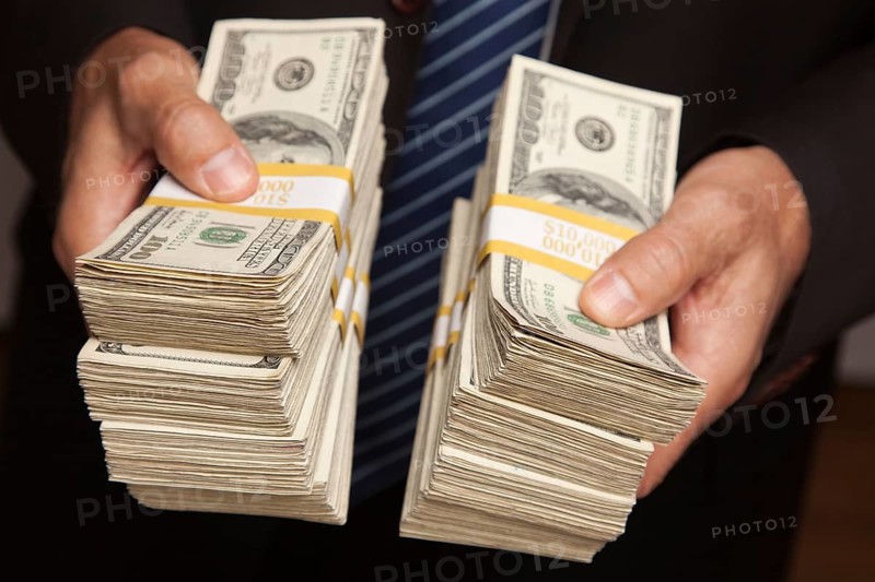 Businessman handing over stacks of hundred dollar bills
