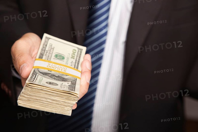 Businessman handing over stack of one hundred dollar bills