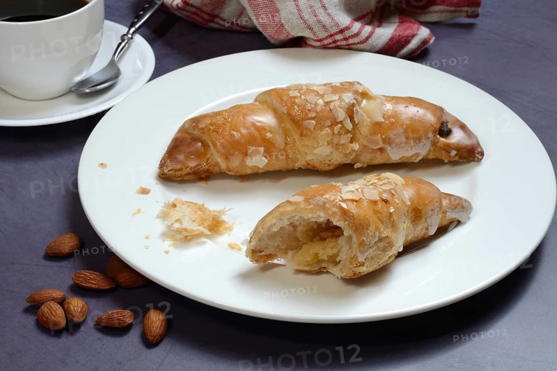 Almond croissant on plate with coffee cup