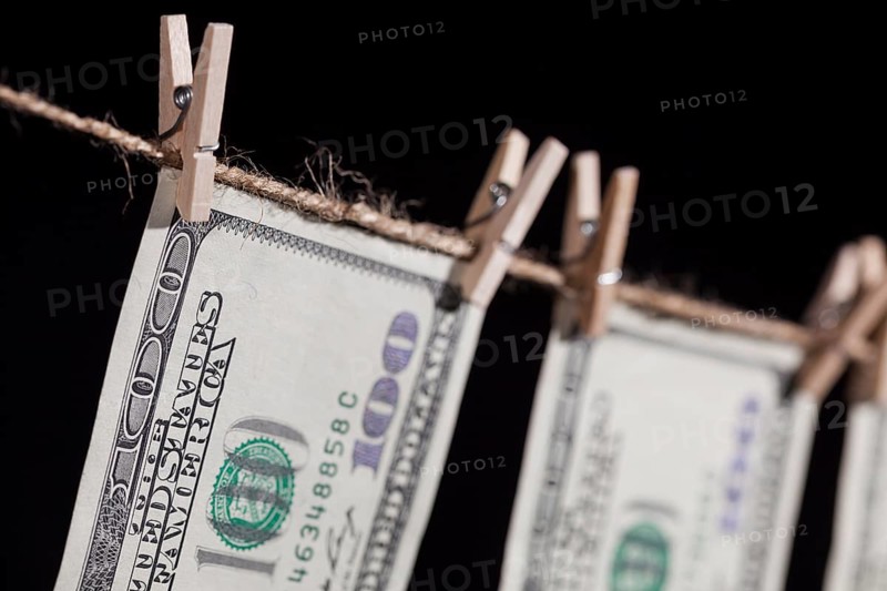 Hundred dollar bills hanging from a clothesline on a dark background