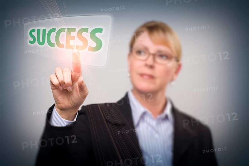 Attractive blonde woman pushing success button on an interactive touch screen