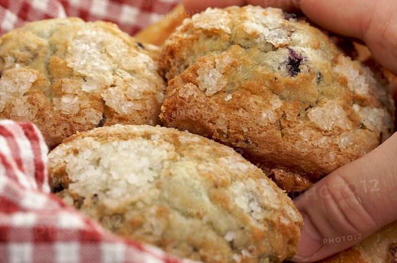 Man's hand grabbbing for blueberry muffins in basket