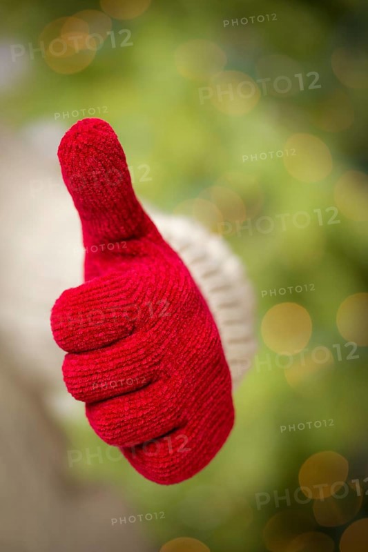 Woman in sweater with seasonal red mittens holding out a thumb up sign with her hand