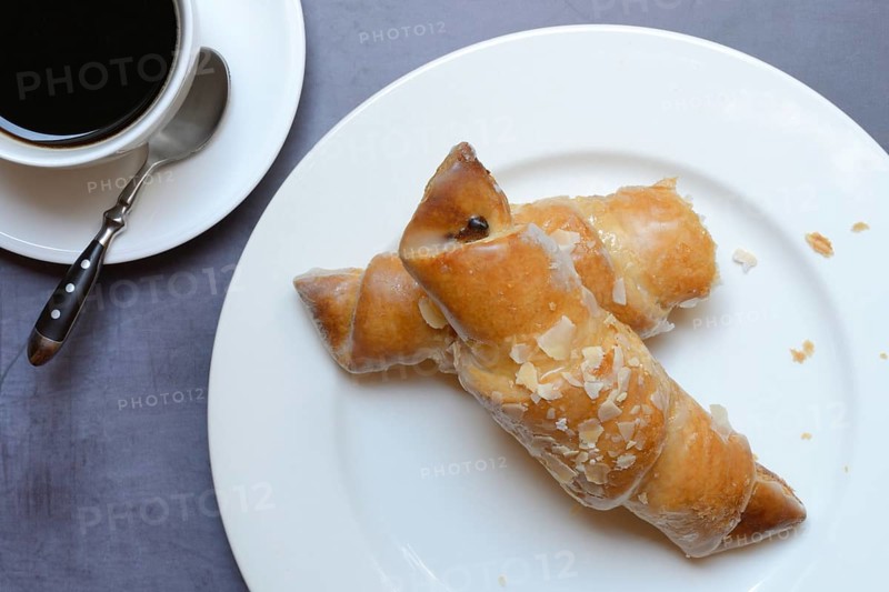 Almond croissant on plate with coffee cup