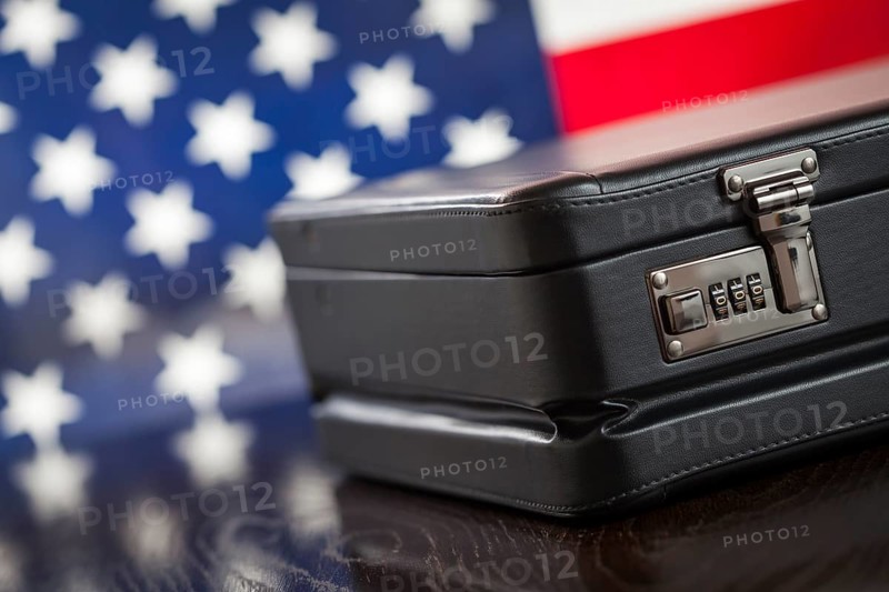 Black leather briefcase resting on table with american flag behind