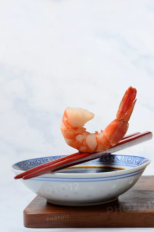 Cooked shrimp on chopsticks and shell with soy sauce