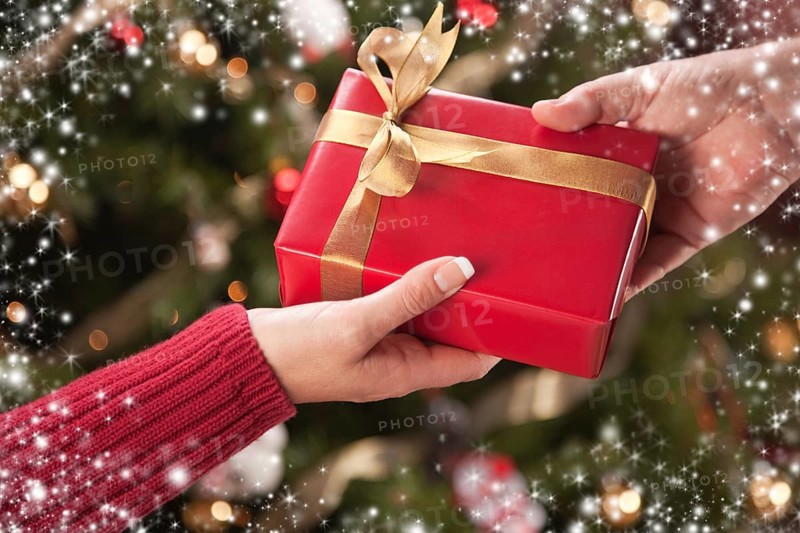 Man and woman gift exchange in front of decorated christmas tree with snow flakes border