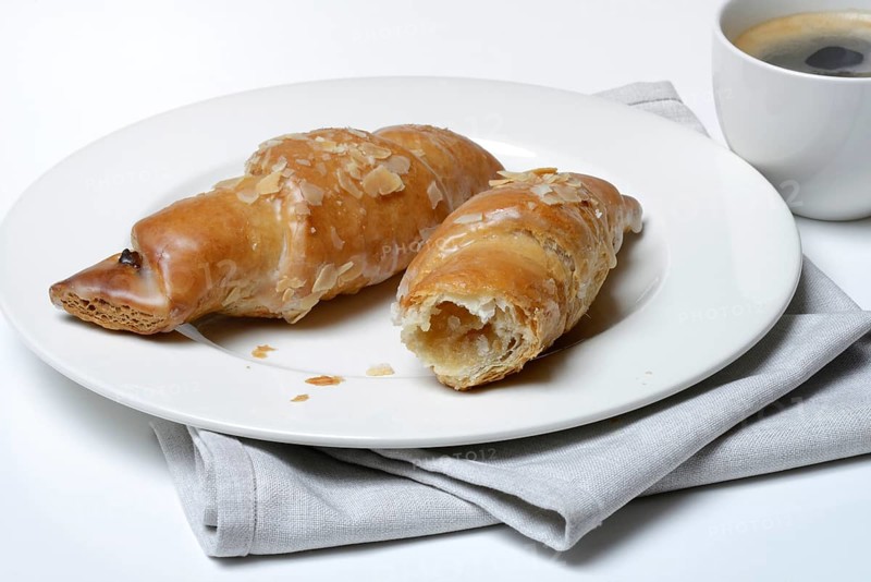 Almond croissant on plate with coffee cup