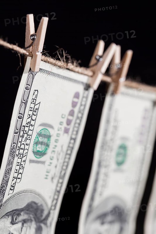 Hundred dollar bills hanging from a clothesline on a dark background