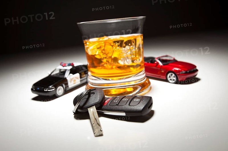 Highway patrol police and sports car next to alcoholic drink and keys under spot light