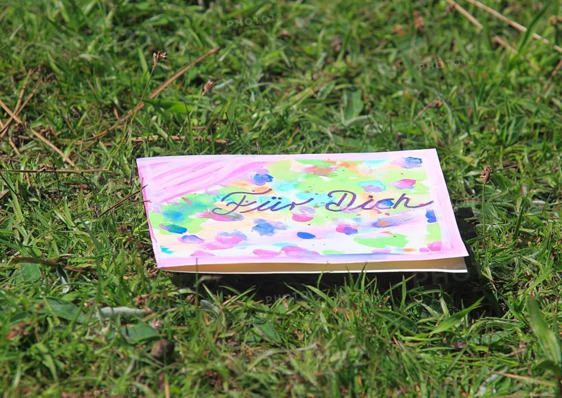 Self painted greeting card lies in a meadow