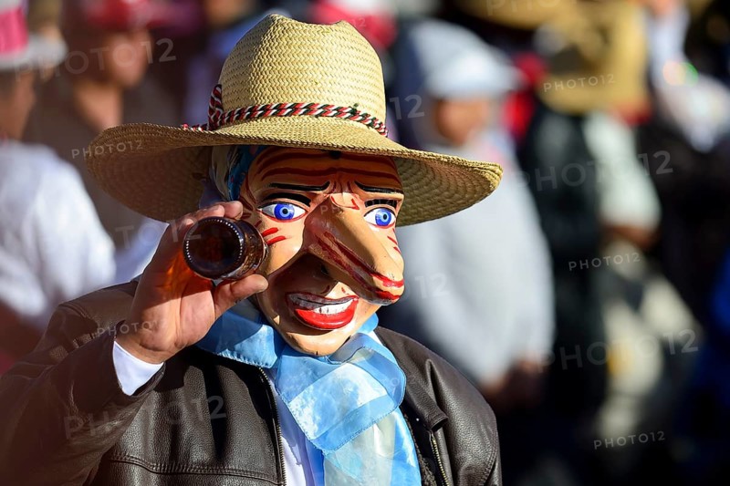 Mask of a man with a beer bottle at the parade on the eve of Inti Raymi