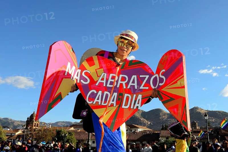 Stilt walkers with sign More hugs every day at parade on eve of Inti Raymi