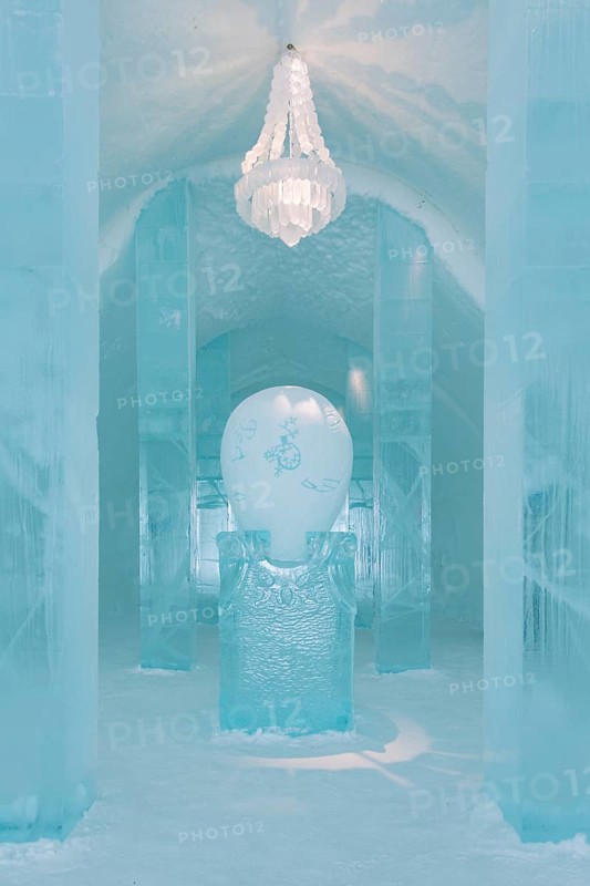 Long corridor with table and chandelier made of ice in the ice hotel of Jukkasjaervi
