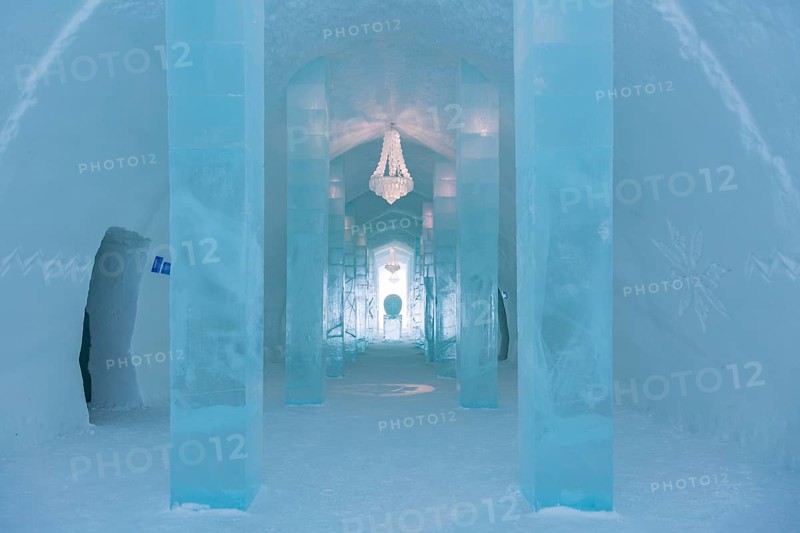 Long corridor with table and chandelier made of ice in the ice hotel of Jukkasjaervi