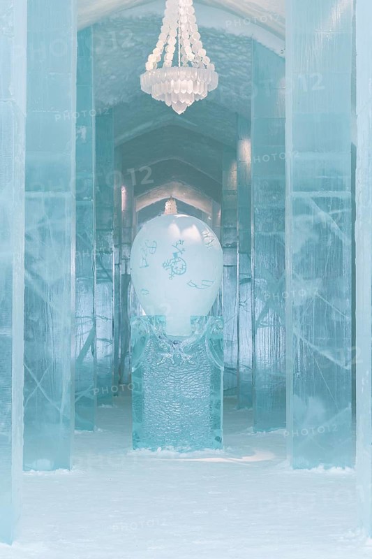 Long corridor with table and chandelier made of ice in the ice hotel of Jukkasjaervi