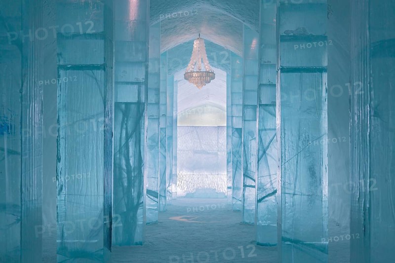 Long corridor with table and chandelier made of ice in the ice hotel of Jukkasjaervi