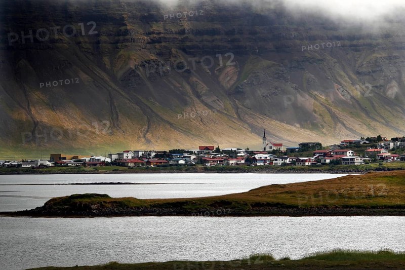Fishing village on headland in front of mountain scenery