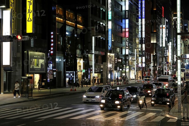 Illuminated street with neon lights and cars in traffic in Ginza district