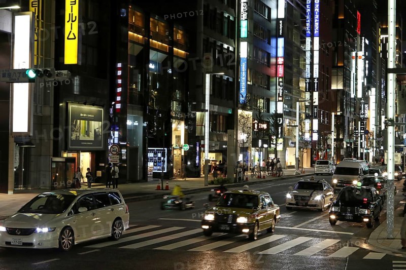 Illuminated street with neon lights and cars in traffic in Ginza district
