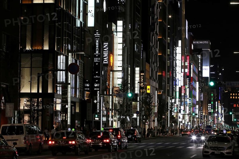 Illuminated street with neon lights and cars in traffic in Ginza district