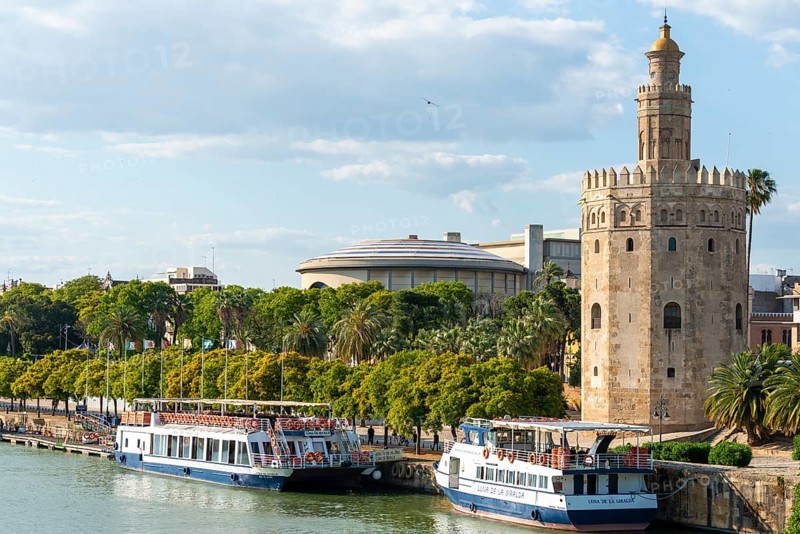 View over the river Rio Guadalquivir on promenade with excursion boats and Torre del Oro