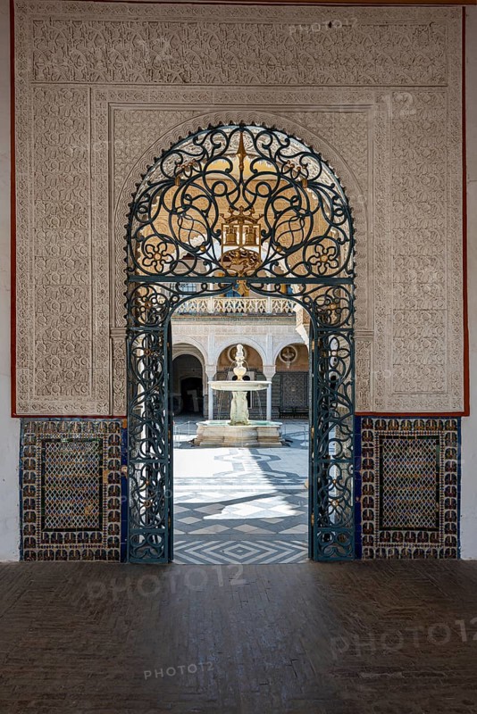 View through a door decorated with arabesques into the inner courtyard with fountain