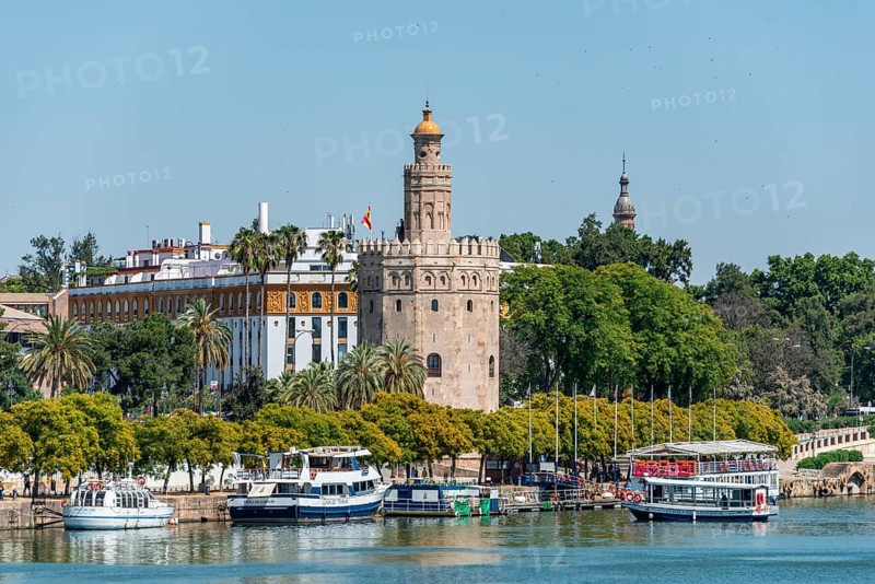 View over the river Rio Guadalquivir on promenade with excursion boats and Torre del Oro