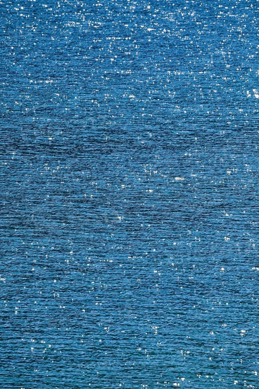 Sunbeams reflect glittering on the water surface of the Vierwaldstaettersee and form an abstract pattern