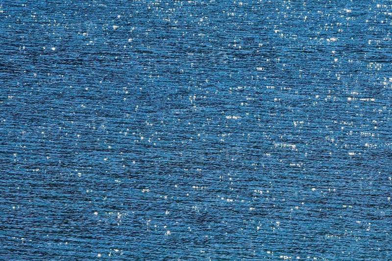 Sunbeams reflect glittering on the water surface of the Vierwaldstaettersee and form an abstract pattern