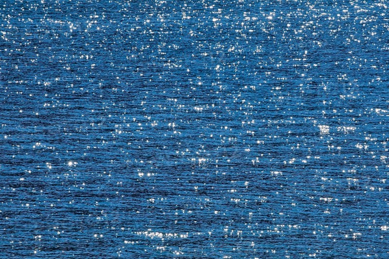 Sunbeams reflect glittering on the water surface of the Vierwaldstaettersee and form an abstract pattern