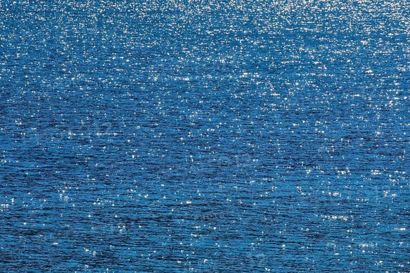 Sunbeams reflect glittering on the water surface of the Vierwaldstaettersee and form an abstract pattern