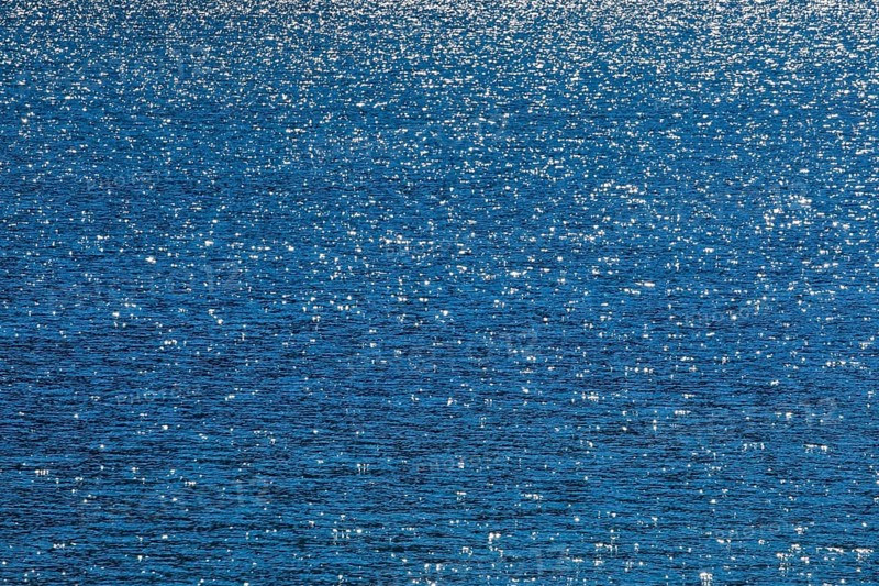 Sunbeams reflect glittering on the water surface of the Vierwaldstaettersee and form an abstract pattern