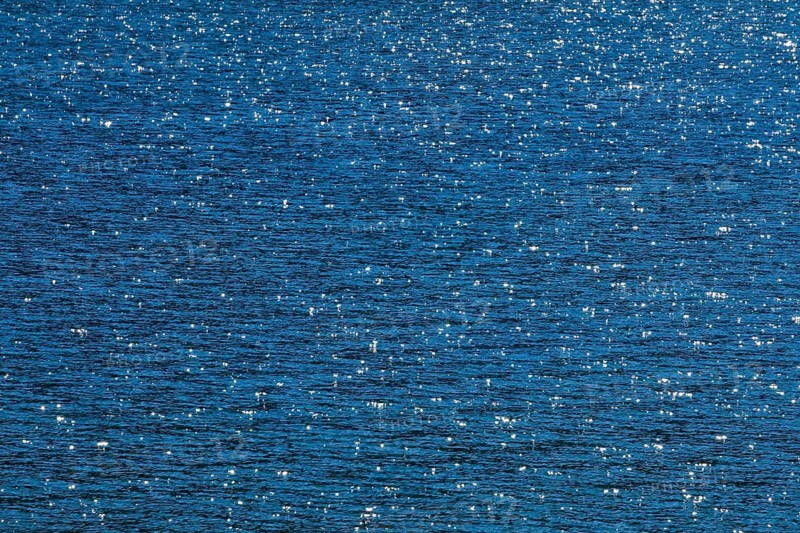 Sunbeams reflect glittering on the water surface of the Vierwaldstaettersee and form an abstract pattern