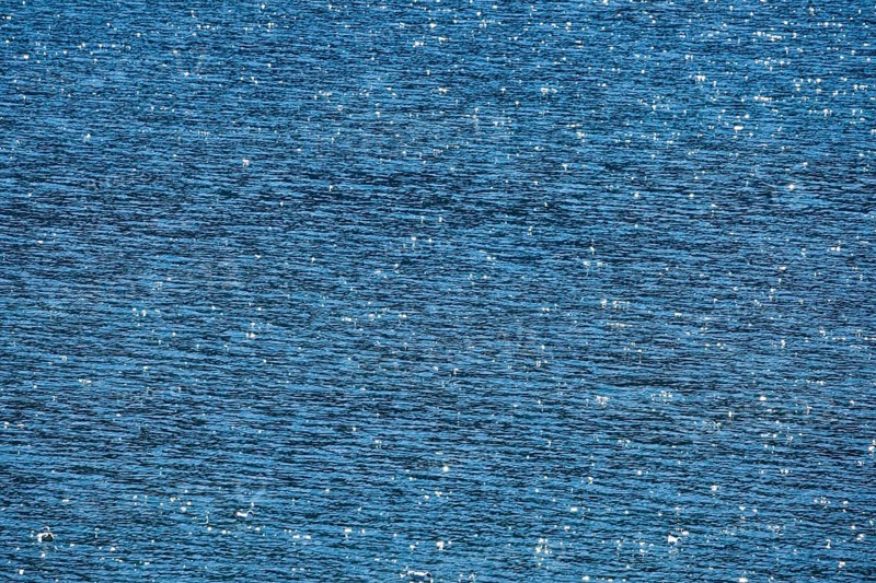 Sunbeams reflect glittering on the water surface of the Vierwaldstaettersee and form an abstract pattern