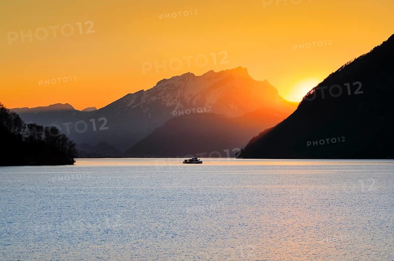 View from Brunnen on a boat on the Vierwaldstaettersee with Pilatus in the background at sunset