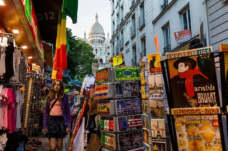 Street with souvenir shops on Montmartre with the Basilica Sacre-Coeur in the background